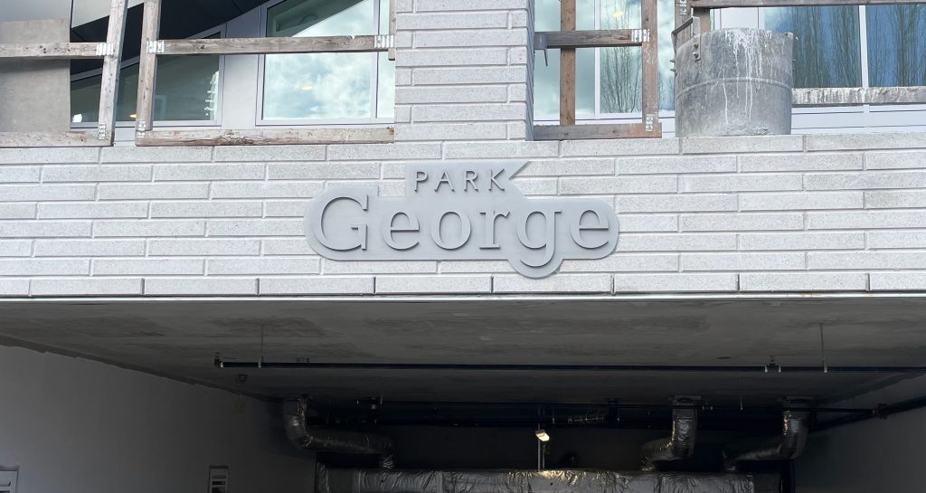 Grey acrylic sign overtop a parkade entrance reading "Park George"